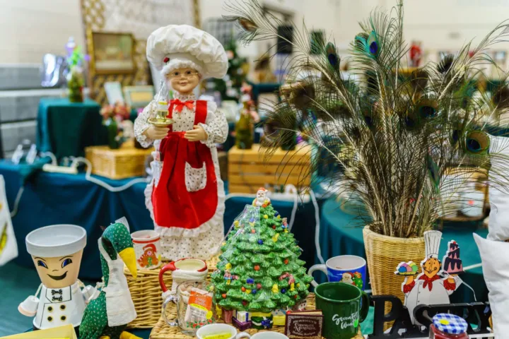 A decorative display features a chef doll, a green Christmas tree, and various festive items on a table.