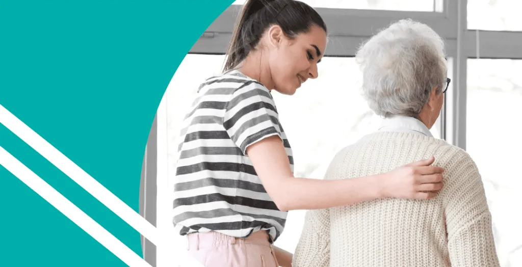 A young woman assists an older woman while walking, both facing away from the camera in a bright indoor setting.