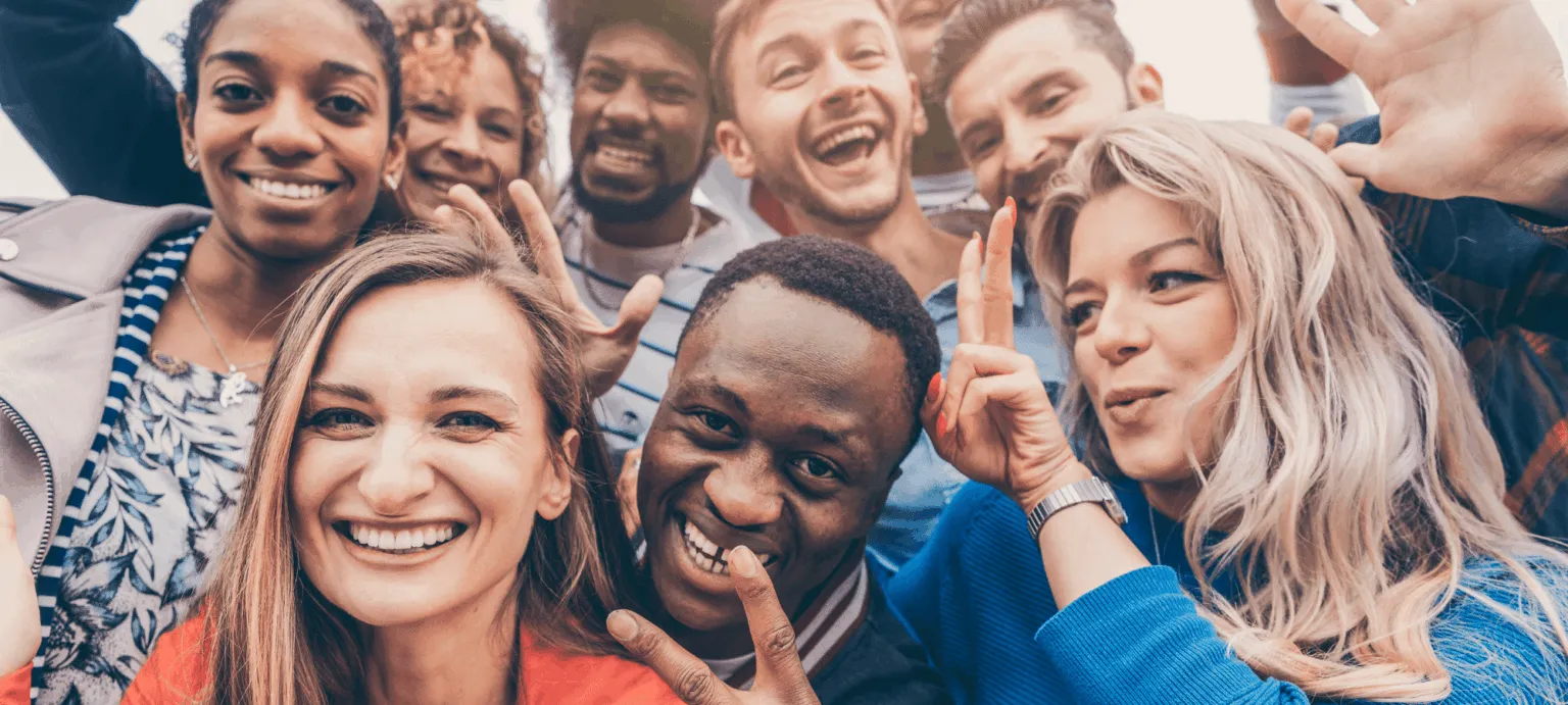 Group of diverse individuals smiling and posing playfully for the camera during a gathering.
