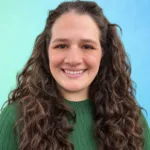 A person with curly hair smiles while wearing a green sweater against a blue and green background.